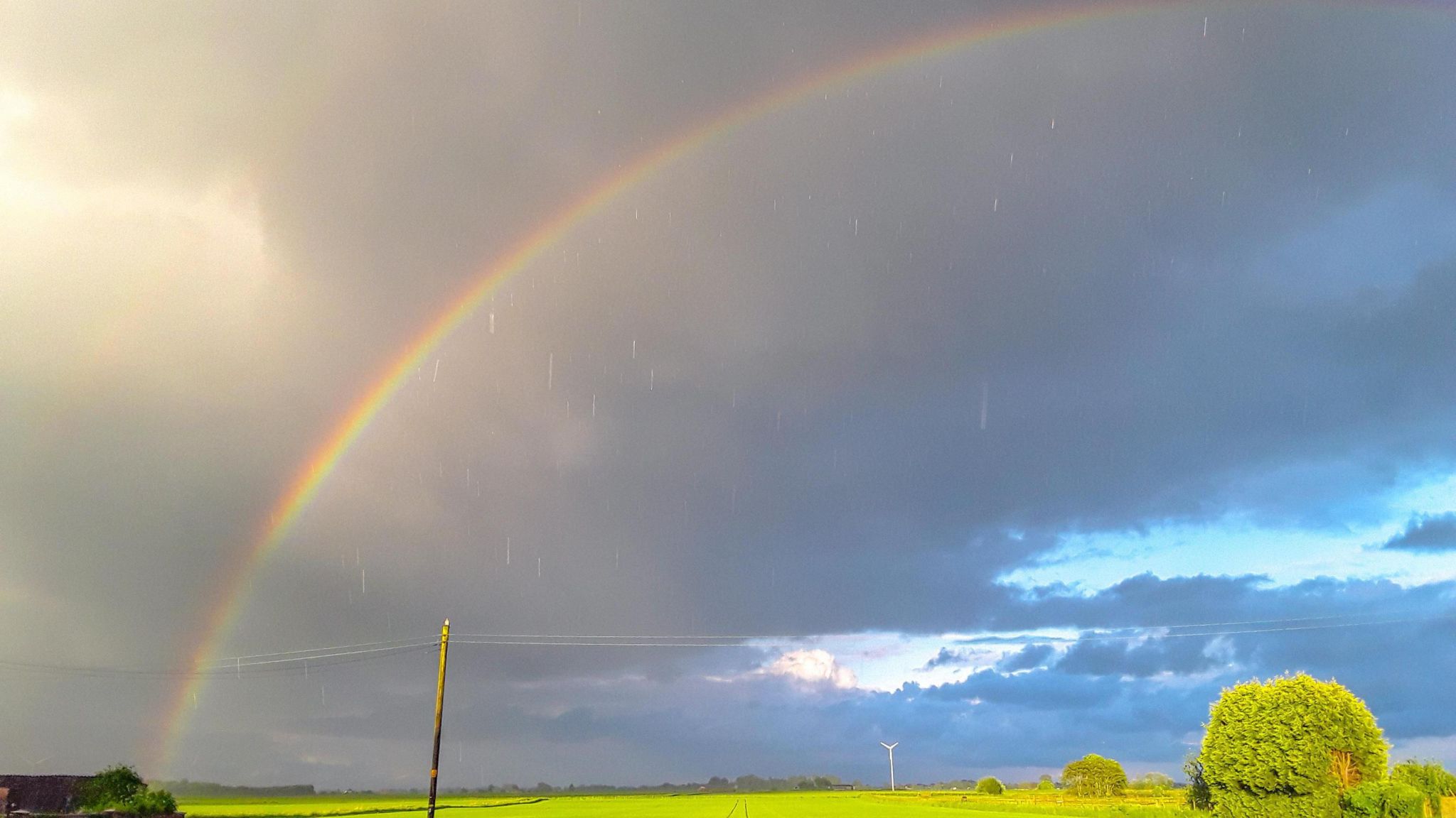 A rainbow over a field with sunshine and raindrops